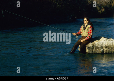 Pêche à la mouche femme debout dans l'eau portant une chemise de flanelle rouge Banque D'Images