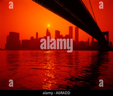 Lower Manhattan à New York vu au coucher du soleil depuis le dessous de la travée du pont de Brooklyn, l'autre côté de l'East River Banque D'Images