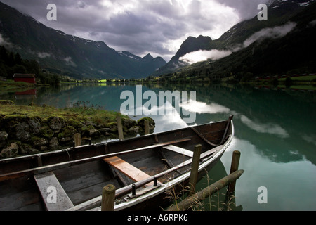 Un bateau à rames est intégré en toute sécurité dans les eaux turquoises du lac Olden, tandis qu'un ciel d'orage menaçant au-dessus de la Norvège se bloque Banque D'Images