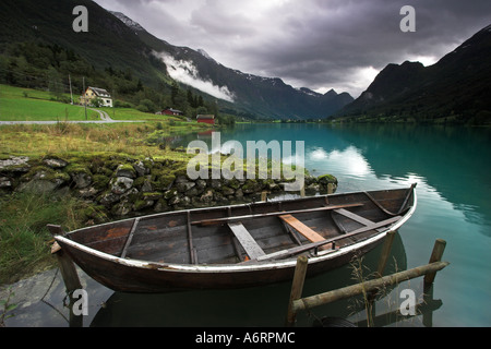 Un bateau à rames est attaché dans le miroir comme l'eau turquoise du lac Olden, Norvège Banque D'Images