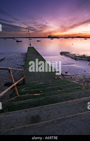 Une jetée en béton à Burnham on Crouch dans l'Essex. Les couleurs du crépuscule se reflètent dans la rivière calme ; bateaux sont amarrés en toute sécurité Banque D'Images