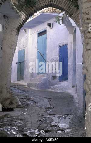 L'Afrique, Maroc, Chefchaouen (aka Chaouen), Bleu des portes dans des murs blanchis à la vue à travers l'arc de cobblestone alley Banque D'Images