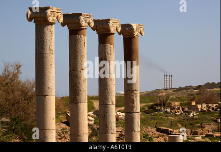 Quatre colonnes romaines près de l'ancien Forum à Leptis Magna en Libye sont repris par les cheminées d'une centrale électrique à proximité Banque D'Images