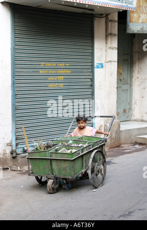 Très jeune garçon pousse sa mère panier d'ordures dans les rues d'Ahmedabad Gujarat Inde Banque D'Images