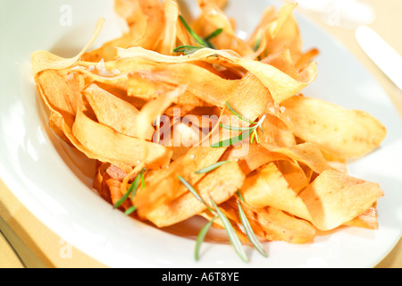 Golden fried chips de légumes racines servi dans une assiette blanche avec le romarin et le sel de mer Banque D'Images