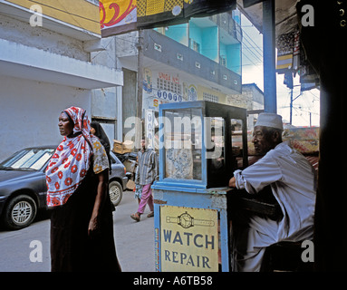 Afrique Kenya Mombasa musulman la vente de montres de stand de la rue musulmane comme les piétons marchent par Banque D'Images