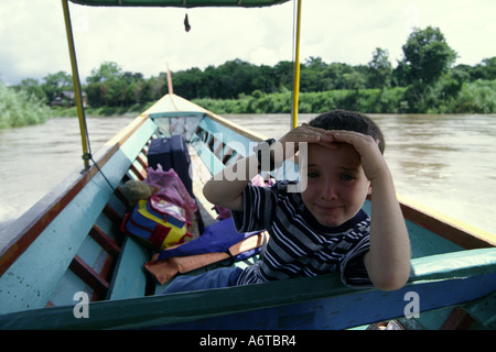 Western garçon voyageant par bateau à longue queue sur la rivière Mae Nam Kok Thaïlande du Nord Banque D'Images