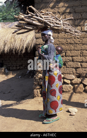 L'Afrique, l'ouest de la Tanzanie rurale Femme portant enfant et bois de chauffage Banque D'Images