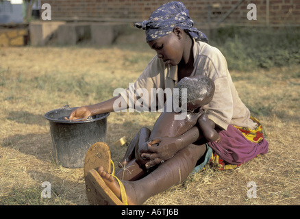 L'Afrique, Tanzanie, les zones rurales de l'ouest de la Tanzanie. Femme baigne son enfant malade à l'extérieur de l'hôpital Banque D'Images