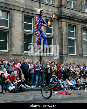 Artiste de la rue de sexe masculin d'effectuer sur un monocycle tout en jonglant avec des torches de feu au Festival Fringe d'Ecosse UK 2004 Banque D'Images