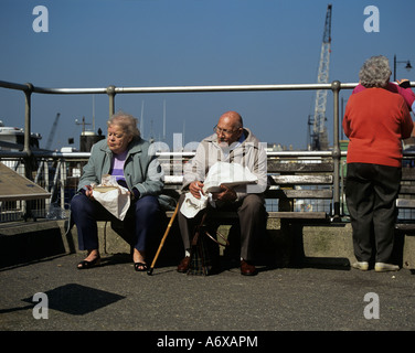 WEST SUSSEX UK Mars un couple de personnes âgées assis sur un banc à côté du port bénéficiant d''un déjeuner fish and chips Banque D'Images