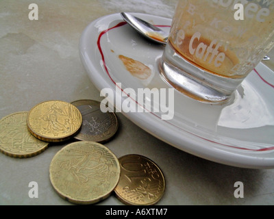 Tasse vide glas d'expresso expresso avec des pièces de monnaie sur la table Banque D'Images