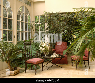 Chaises avec tissus rouges dans la véranda extension avec des plantes d'intérieur Banque D'Images