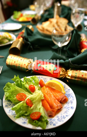Portrait format image d'une table de dîner de Noël décoré avec des craquelins, et saumon fumé starter en premier plan. Banque D'Images