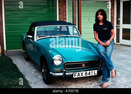 Fille pose assis sur le capot de sa voiture de sport MG Midget 1970 Banque D'Images