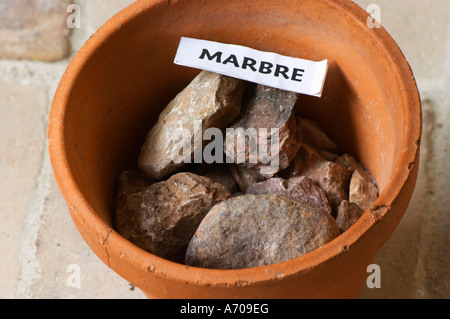 Plante en pot échantillon de sol pour illustrer les différents types de sol, partie d'une série : rocher de marbre, marbre. Château Villerambert-Julien près de Caunes-Minervois. Minervois. Languedoc. Terroir le sol. La France. L'Europe. Les roches du sol avec des pierres. Banque D'Images