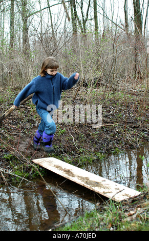 Enfant sautant sur pont sur stream Banque D'Images