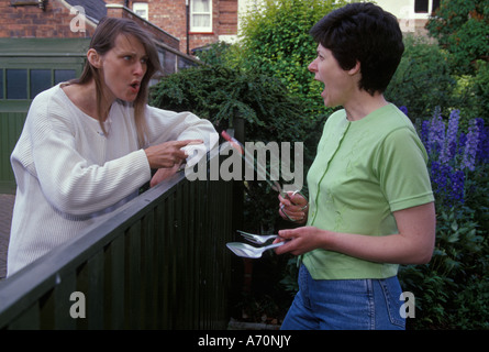 Deux femmes se battre à la barrière au sujet de barbecues Banque D'Images