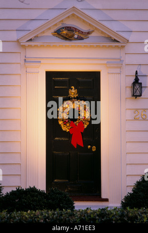Cône de pin doré allumé Spot couronne, avec un arc rouge suspendu à une porte avant noir pour un cadre blanc chambre Banque D'Images
