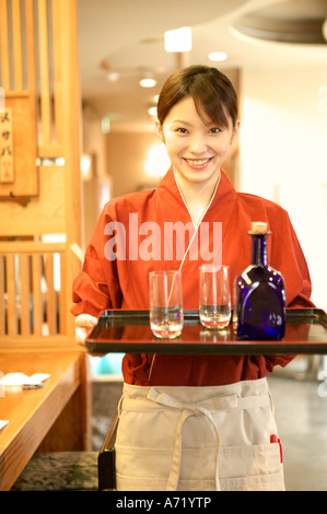 Waitress holding tray de verres et bouteille Banque D'Images