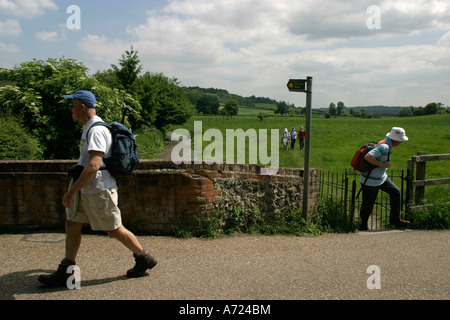 Randonneurs sur le chemin de marche si Chiltern à travers champs dans le village de Hambleden Banque D'Images