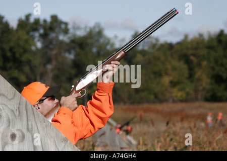 Un chasseur tirer sur les oiseaux qui arrivent au cours d'un oiseau sur tige. Banque D'Images