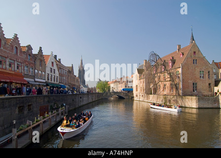 Paysage urbain horizontal depuis le canal de Rozenhoedkaai avec un bateau d'excursion plein de touristes au soleil à Bruges. Banque D'Images