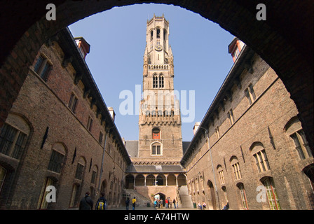 Large angle horizontal du beffroi incliné de Bruges ou du Belfort van Brugge depuis la cour intérieure pavée, par une journée ensoleillée à Bruges. Banque D'Images