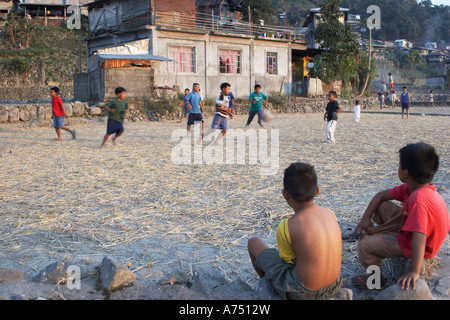 Les enfants jouaient au football dans Paddyfield Banque D'Images