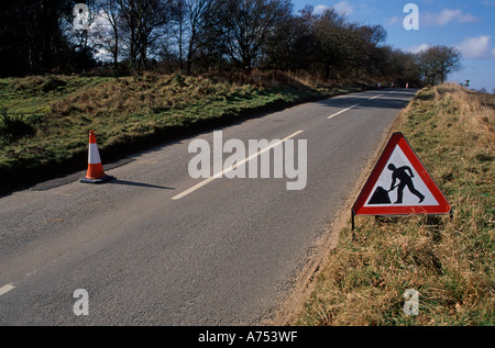 Travaux triangle rouge signe avec la figure de creuser, route de campagne tranquille en Angleterre Banque D'Images