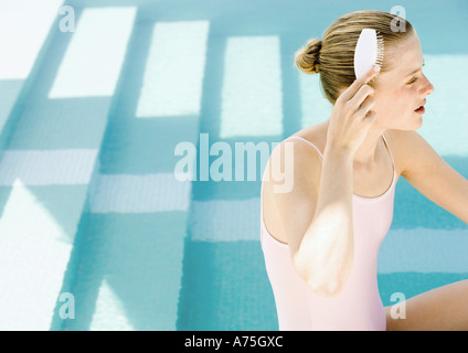 Woman brushing hair à côte de la piscine Banque D'Images