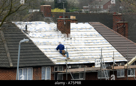 Un travailleur de toiture MET UN NOUVEAU TOIT SUR UNE MAISON À BIRMINGHAM, RE TRAVAILLER EMPLOI SANTÉ ET SÉCURITÉ DES TRAVAILLEURS ET LES COÛTS D'ACCUEIL ETC ANGLETERRE.UK Banque D'Images