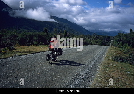 Seule femme randonnée cycliste sur route difficile au Chili en vêtements de pluie Banque D'Images
