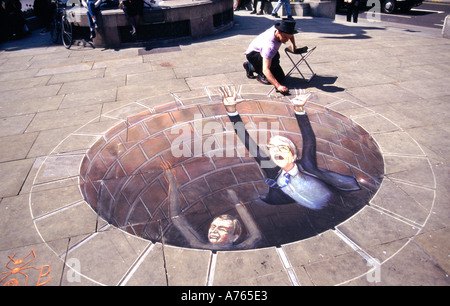 Gros plan de l'artiste de rue de craie Julian Beever au travail sur la caricature politique de Pavement de John Major & Paddy Ashdown tombant dans le puits de trou Londres Royaume-Uni Banque D'Images