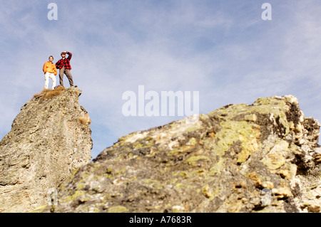 Jeune couple standing on mountain peak, low angle view Banque D'Images