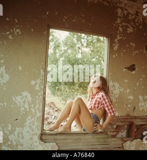 Jeune femme assise dans la fenêtre ancienne maison Banque D'Images