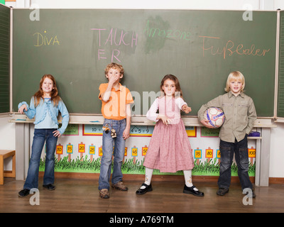 Enfants (4-7) standing in front of blackboard, portrait Banque D'Images