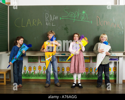 Enfants (4-7) standing in front of blackboard holding cônes école Banque D'Images