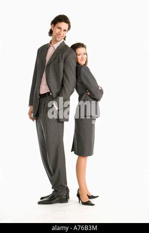 Businessman and businesswoman standing back to back, smiling Banque D'Images