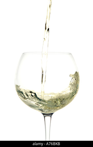 Le vin blanc est versé dans un verre sur un fond blanc, pur. Banque D'Images