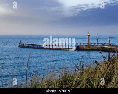 Vue depuis le sommet de la falaise ouest vers le mur du port et le phare sur la jetée ouest à Whitby North Yorkshire UK Banque D'Images