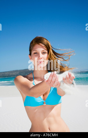 Woman holding sand on beach, portrait Banque D'Images