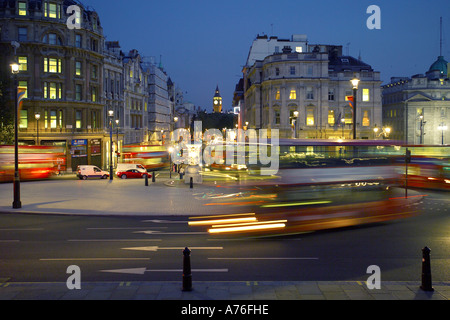 Flou de mouvement l'heure de pointe et les autobus rouges traditionnels autour de Trafalgar Square et de Whitehall avec Big Ben en arrière-plan. Banque D'Images