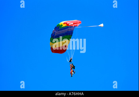 Parachutistes Buddy dans le ciel vers le bas flottant avec un parachute de couleur arc-en-ciel et un fond de ciel bleu. Banque D'Images