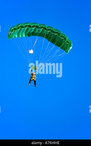 Parachutistes Buddy dans le ciel variable avec un parachute de couleur verte et un fond de ciel bleu. Banque D'Images