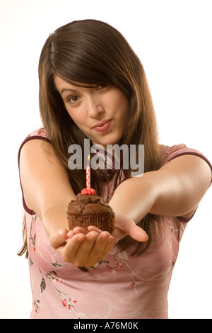 Young woman blowing bougie sur torte, portrait Banque D'Images