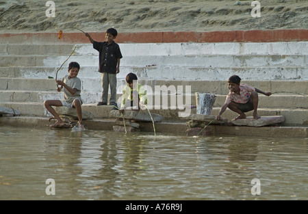 Les enfants pêchent le long de la rivière du Gange à Varanasi, Inde Banque D'Images