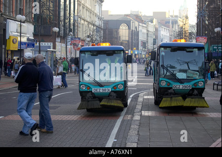 Les piétons passer devant deux balayeuses de rue dans l'avenue Royal pendant les achats de Noël à Belfast la veille de Noël Banque D'Images