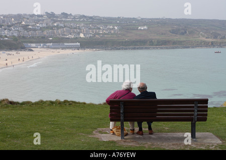 St Ives Cornwall et vieux vieux couple partager une banquette donnant sur la plage de Porthmeor Banque D'Images