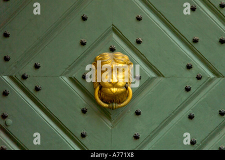 Golden Lion traditionnel sur un heurtoir de porte cloutée vert. Banque D'Images